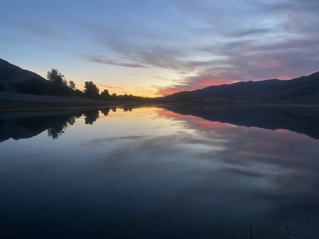 Calm still water at sunset with mountains reflected on the lake
